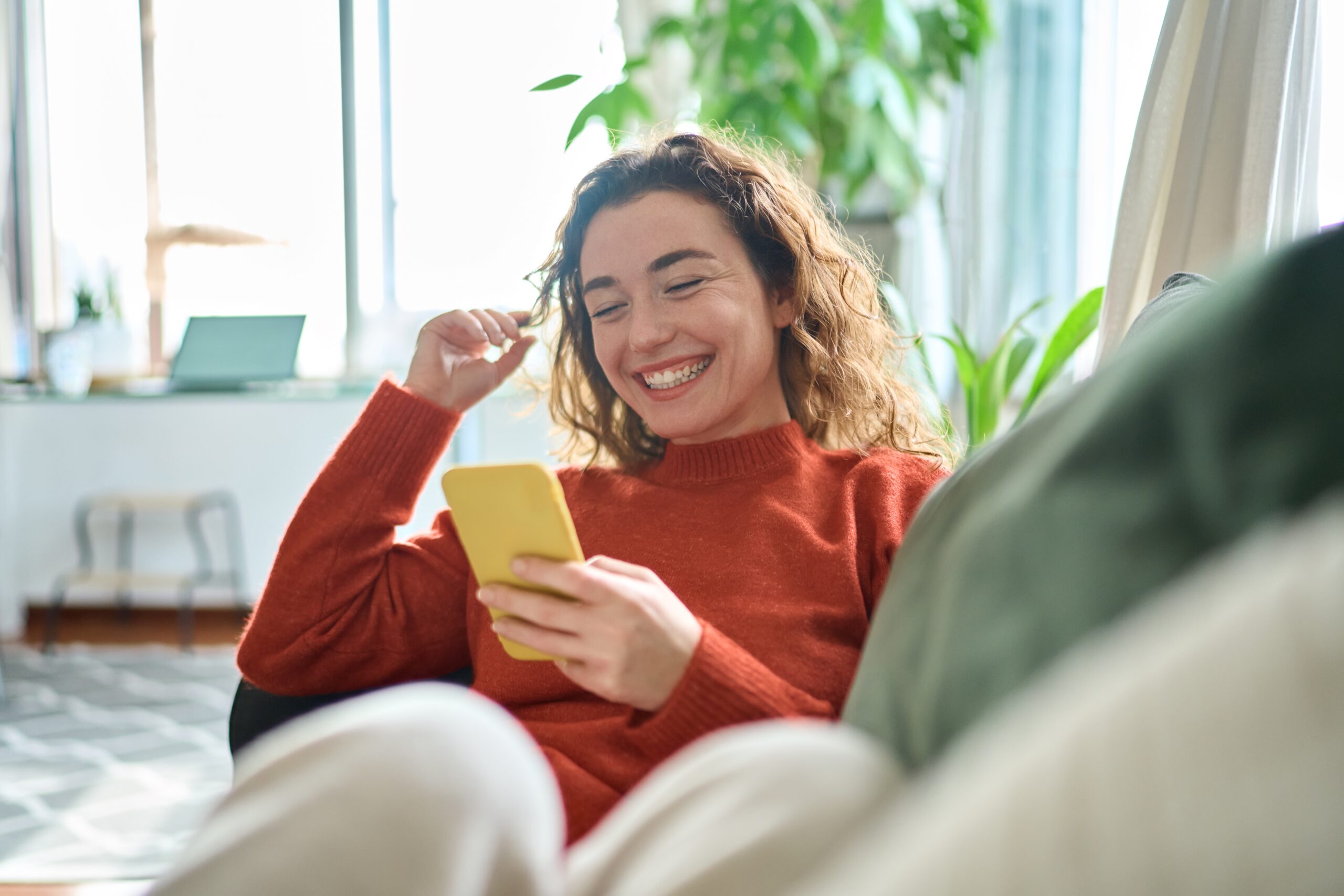 Happy Woman Using Her Smartphone on a Desk